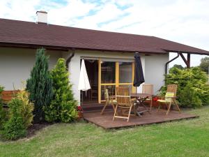 a house with a wooden deck with chairs and an umbrella at Słonecznikowa Zagroda in Debina