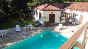 uma casa com piscina em frente a uma casa em Cheiro de Mata Pousada e Restaurante Ltda em Engenheiro Paulo de Frontin