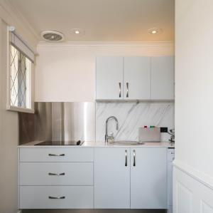 a white kitchen with white cabinets and a sink at Battery Point Boutique Accommodation in Hobart +126 photos