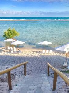a beach with white umbrellas and chairs and the ocean at Samoa Beach Resort in Porto De Galinhas