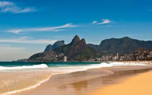 a beach with mountains and the ocean and a city at Studio Top Ipanema in Rio de Janeiro