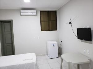 Dieses weiße Zimmer verfügt über einen Kühlschrank und einen TV. in der Unterkunft Excelsior Hotel in Caxias das Aldeias Altas