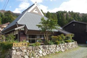 a house with a stone wall in front of it at Taraichitei in Takashima