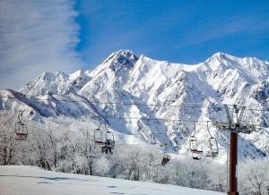 un impianto di risalita di fronte a una montagna innevata di Anri a Hakuba