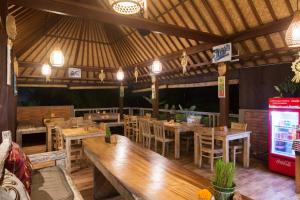 ein Restaurant mit Holztischen und -stühlen sowie einem TV in der Unterkunft Kiskenda Cottages & Restaurant in Ubud