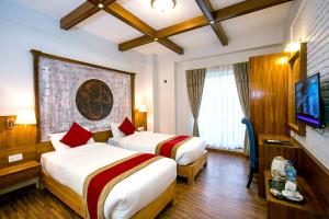 a hotel room with two beds and a flat screen tv at Beautiful Kathmandu Hotel in Kathmandu