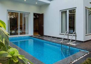 a swimming pool in front of a house at Villa Esencia by VEO - Part of StayVista in Siolim