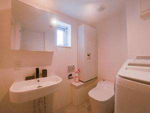 a white bathroom with a sink and a toilet at AOCA KAMINOGE 201 in Tokyo