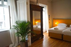 a bedroom with two beds and a mirror and a plant at Hidesign Athens Apollon Luxury Apt in Plaka Acropolis in Athens