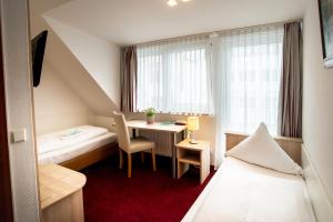 a hotel room with a bed and a desk and a table at Hotel Domblick Garni in Cologne