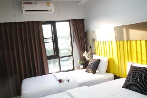 a hotel room with two beds and a window at Bangkok Boutique Resort Rangsit in Pathum Thani
