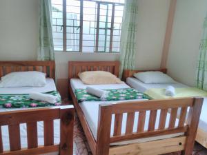 two twin beds in a room with windows at Savta Homestay in Banaue