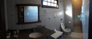 a bathroom with a sink and a toilet and a mirror at Pousada Lagoa Pequena in Prado