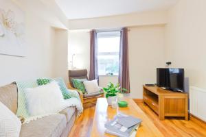 een woonkamer met een bank en een tv bij Five Lamps Suites in Dublin