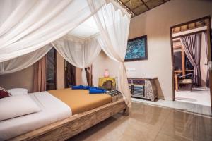 a bedroom with a bed with white drapes at Gajah Biru Bungalows in Ubud +34 photos