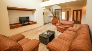 Una sala de estar con un sofá y sillas y un televisor. en Falcon Suites Yelahanka New Town, en Bangalore