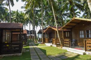 a row of cottages on the beach with palm trees at Agonda Paradise in Agonda