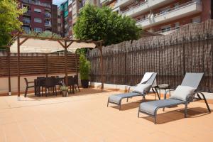 a patio with chairs and a table and a fence at EasySleep Eixample in Barcelona