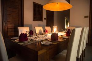 a dining room table with chairs and a long table with wine glasses at Kevans Casa in Mahiyangana