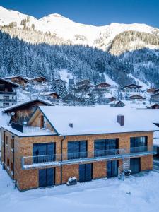 a building in the snow with mountains in the background at Fetz Luxury Appartements in Steeg