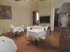 une salle à manger avec des tables et des chaises blanches dans l'établissement Locanda Al Portone, à Scandiano