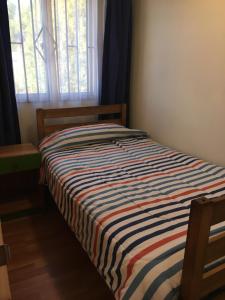 Una cama en un dormitorio con una manta a rayas. en Casa frente a la playa, en Valdivia