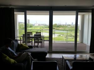 een persoon op een bank in een woonkamer met uitzicht op een tafel bij Infinity I, 0405 in Oostende