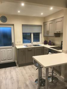 a kitchen with white cabinets and a large window at 8 Queenora Avenue in Portstewart