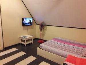 a bedroom with a bed and a tv on a wall at Maznah Guest House in Cherating