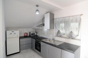 a white kitchen with a sink and a refrigerator at Apartment Olive in Jovići