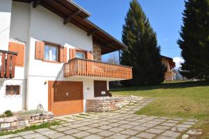 a house with a wooden door and a balcony at GRAZIOSA BIFAMILIARE AD ASIAGO con giardino privato in Asiago