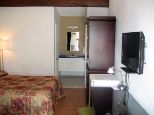 a hotel room with a bed and a flat screen tv at Motel Iberville in Saint-Jean-sur-Richelieu