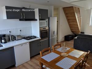 a kitchen and dining room with a wooden table and a table and chairs at Appartements Boulonnais in Boulogne-sur-Mer