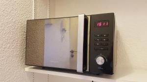 a microwave oven on a wall on a shelf at Studio Oxford in Chevigny-Saint-Sauveur