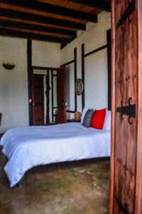 1 dormitorio con 1 cama blanca grande con almohadas rojas en Coffee Tree Boutique Hostel, en Salento