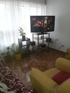 sala de estar con TV de pantalla plana y sofá en Casa de Andrea en Esquel