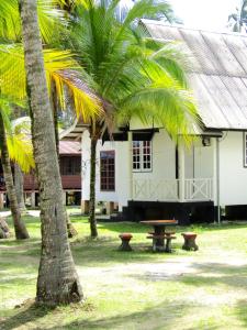 a building with a picnic table and palm trees at Maznah Guest House in Cherating