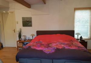a bedroom with a bed with a red blanket and flowers at B&B de Ark in Den Burg