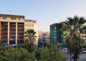 a city skyline with palm trees and buildings at Homely Stay @Acropolis Museum in Athens