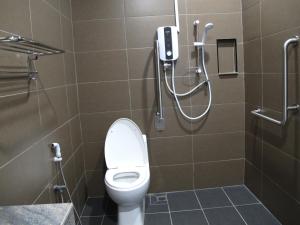 a bathroom with a toilet with a phone on the wall at HOTEL SUKARAMAI in Kampung Gurun