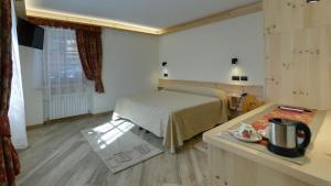 a bedroom with a bed and a kitchen with a table at Hotel Federia in Livigno