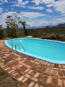 a large blue swimming pool in a yard at Villa Suzana in Praia do Rosa