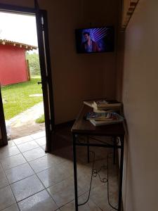a room with a table with a television on the wall at Villa Suzana in Praia do Rosa