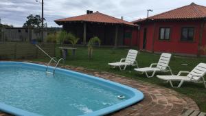 a backyard with a pool and chairs and a house at Villa Suzana in Praia do Rosa