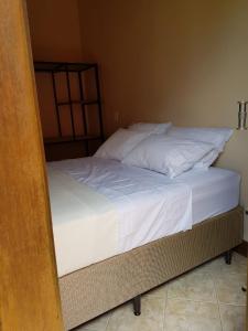 an unmade bed in a bedroom with white sheets at Villa Suzana in Praia do Rosa
