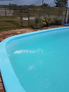 a large blue swimming pool in a yard at Villa Suzana in Praia do Rosa
