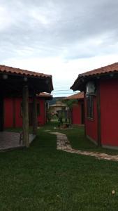 a couple of red buildings with a yard at Villa Suzana in Praia do Rosa