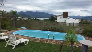 a swimming pool with two lawn chairs and a table at Villa Suzana in Praia do Rosa