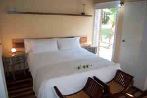 1 dormitorio con 1 cama blanca grande y 2 sillas en Espacio Domu en Cañuelas