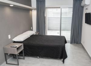 a bedroom with a bed with a table and a window at Dickens Apart in Salta